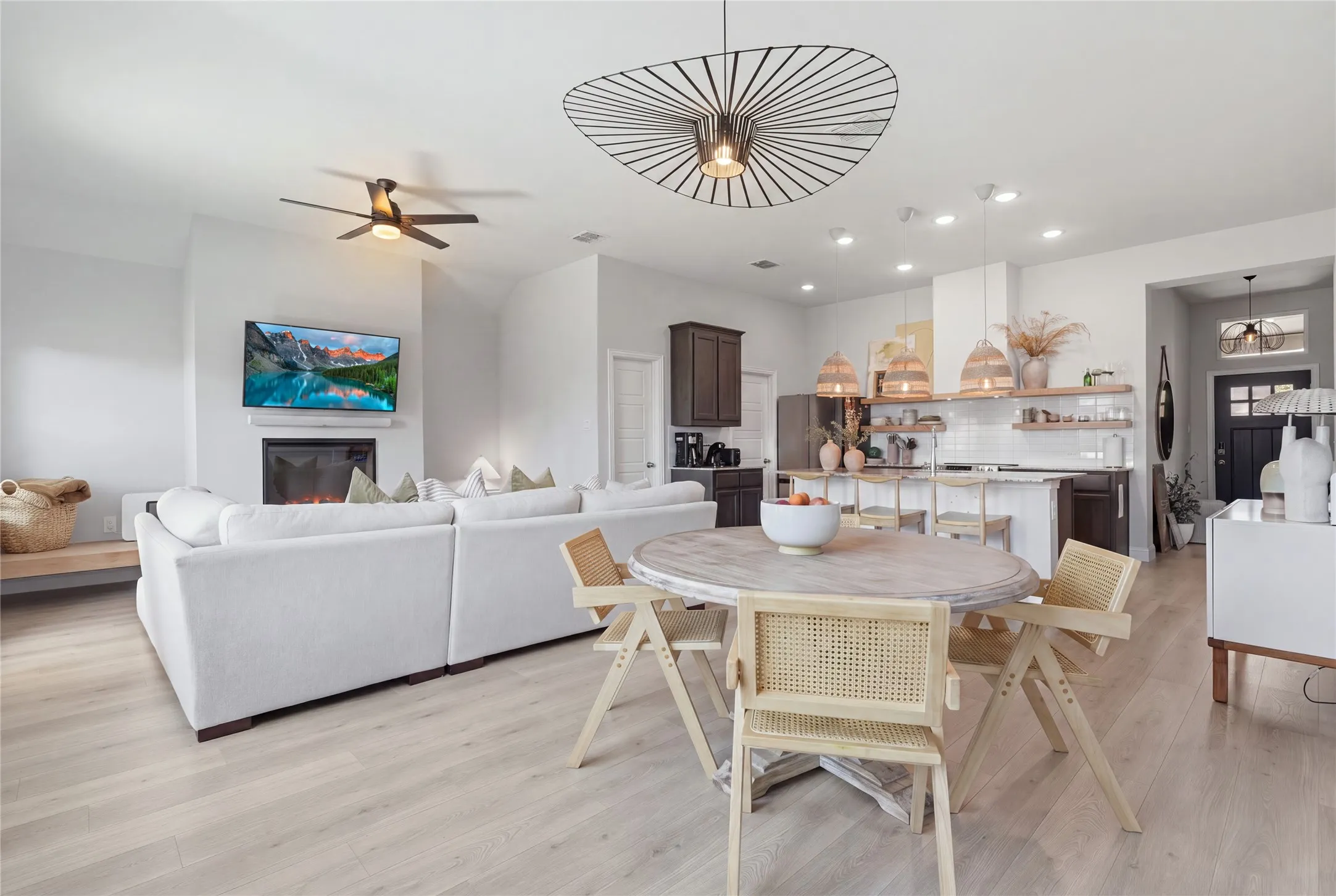 Open-concept living area featuring light wood-finish flooring, a fireplace, and recessed lighting
