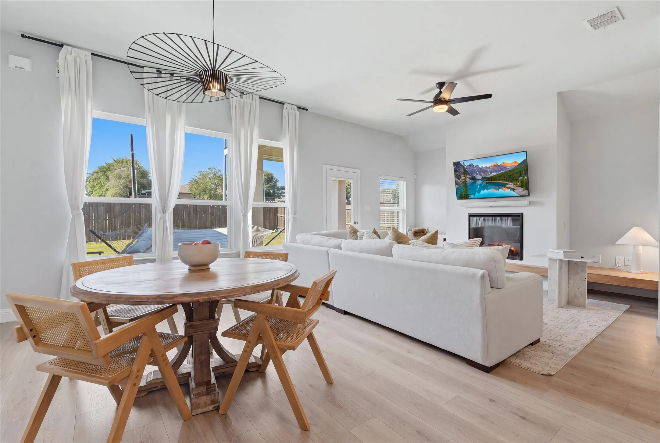 Open-concept living space with wood-finish flooring, a contemporary fireplace, and high ceilings