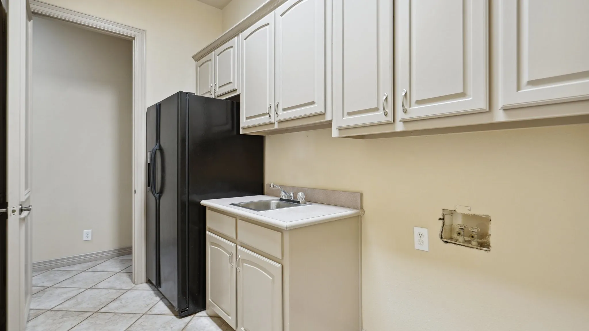 Washroom with a sink, baseboards, cabinet space, and light tile patterned flooring