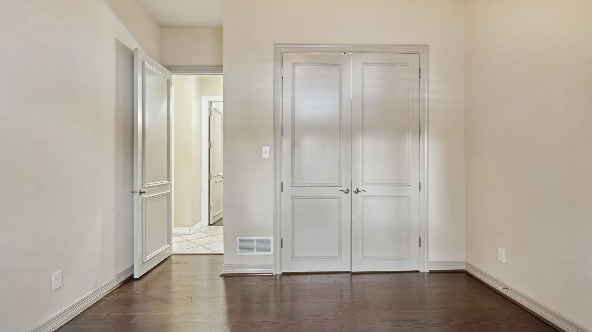 Unfurnished bedroom featuring dark wood-style flooring, baseboards, visible vents, and a closet