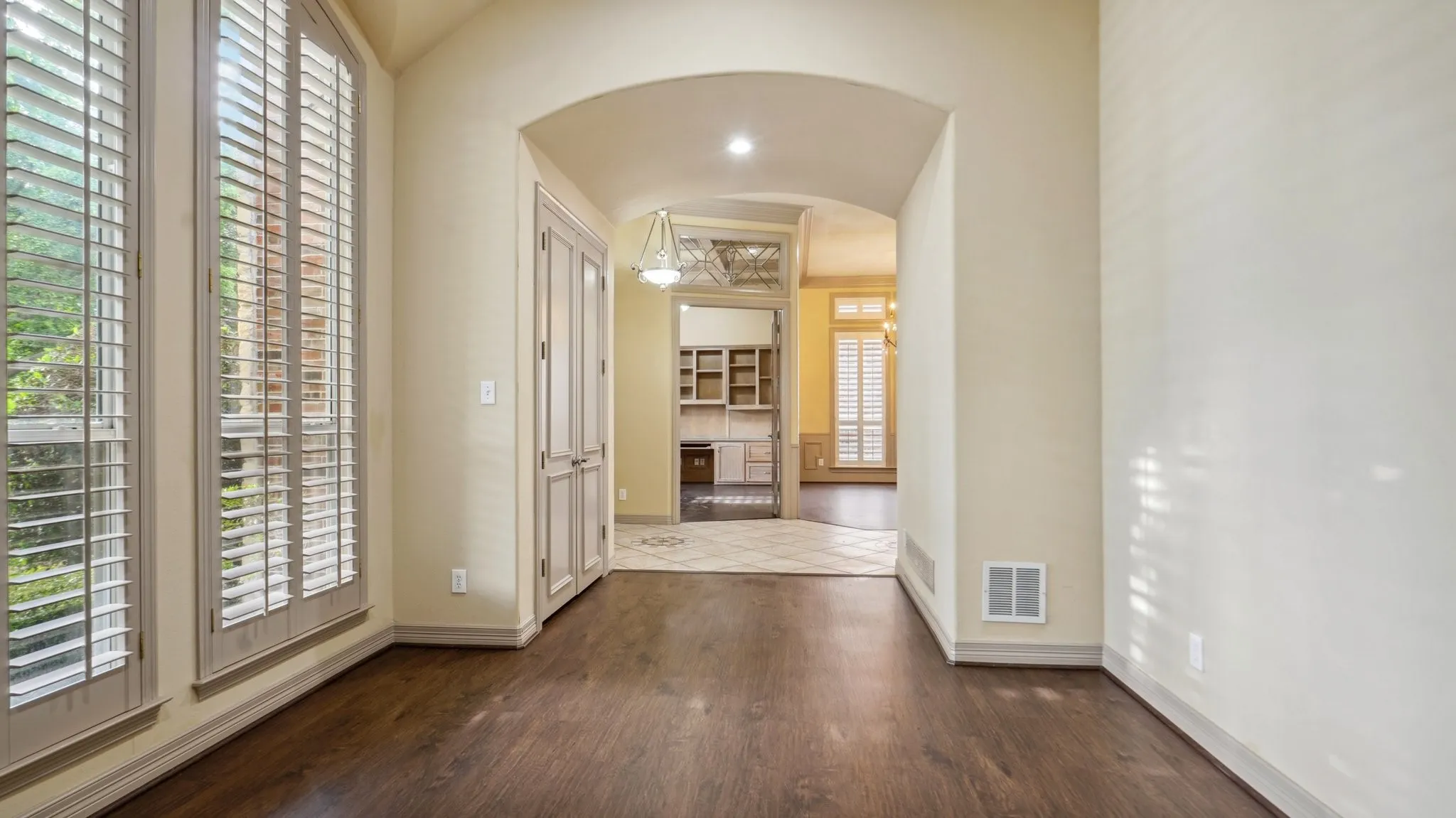 Hallway featuring arched walkways, visible vents, plenty of natural light, and wood finished floors