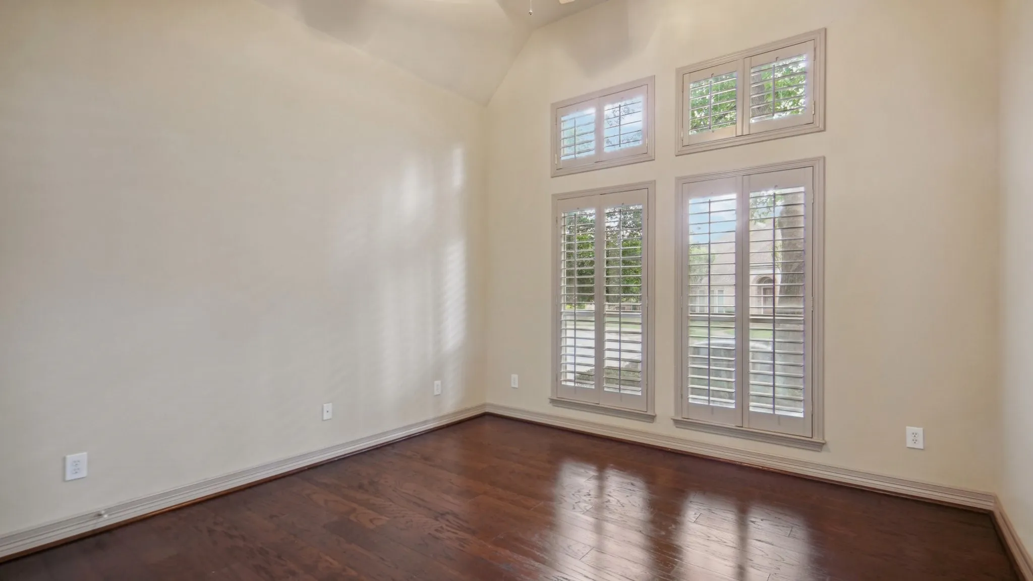 Empty room featuring baseboards, a ceiling fan, dark wood-style floors, and lofted ceiling