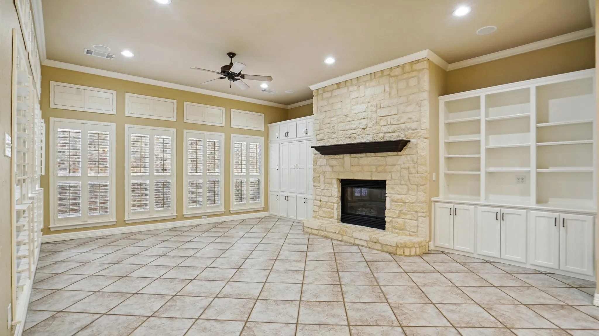 Unfurnished living room featuring ceiling fan, visible vents, crown molding, a fireplace, and light tile patterned floors