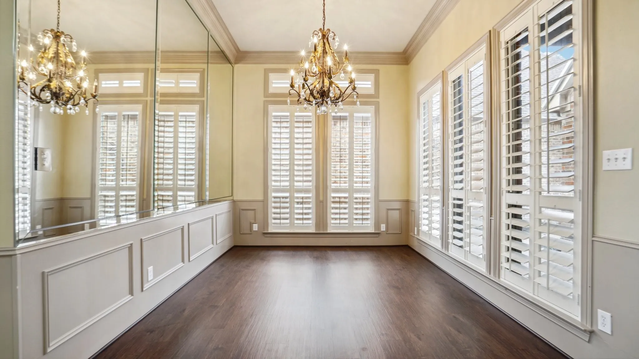 Unfurnished dining area featuring wainscoting, crown molding, a decorative wall, and a notable chandelier