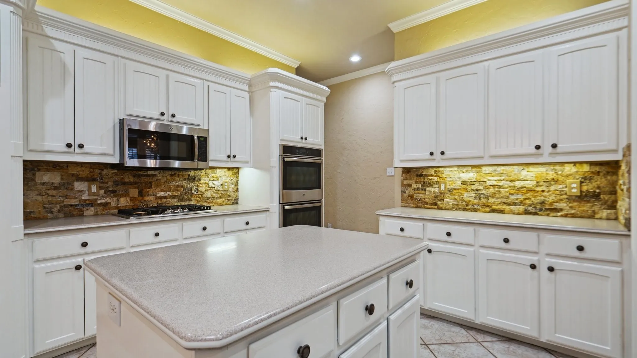 Kitchen featuring light countertops, stainless steel appliances, ornamental molding, and tasteful backsplash