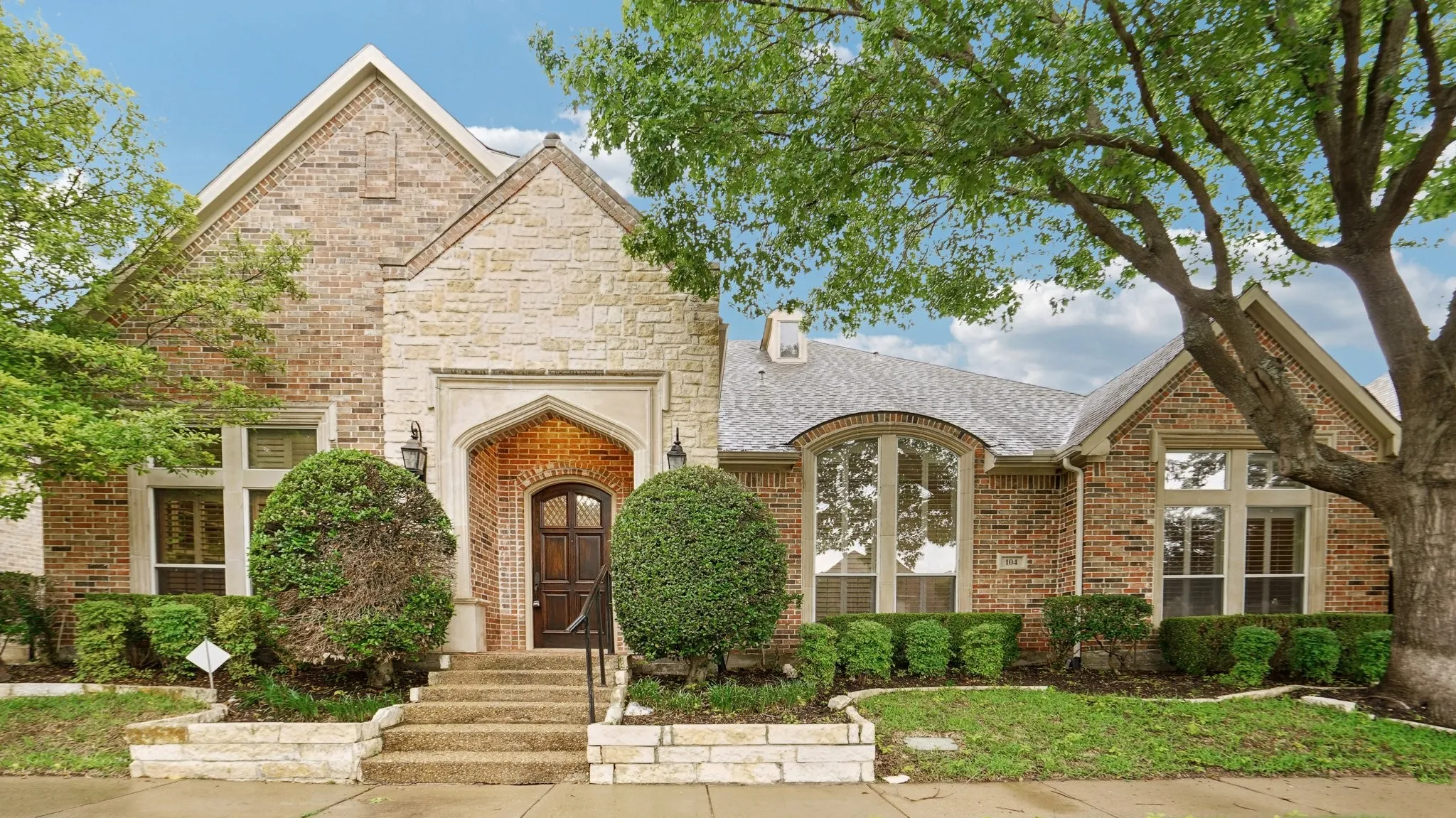French country style house featuring brick siding, a shingled roof, and a chimney