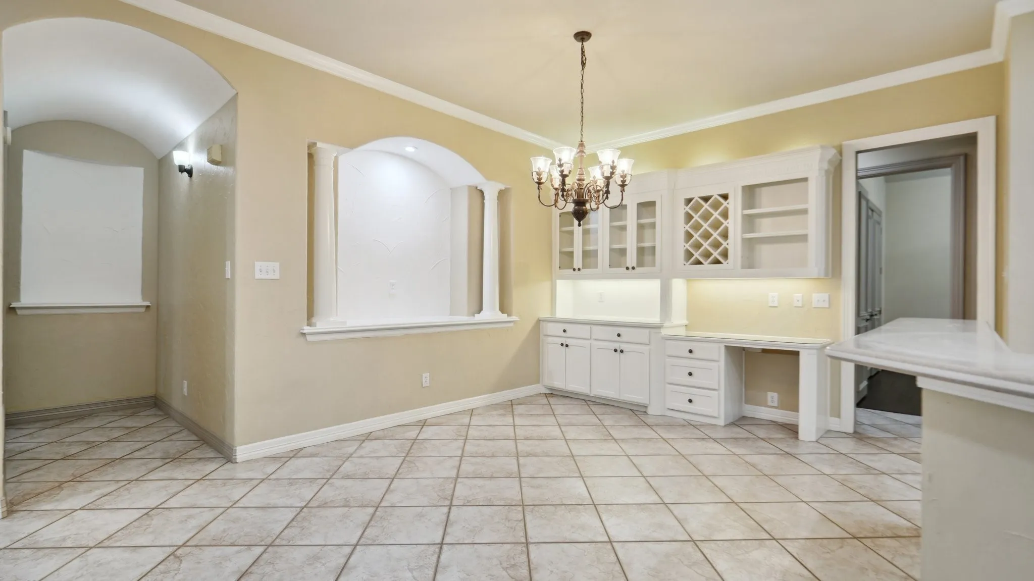 Unfurnished dining area featuring crown molding, baseboards, light tile patterned floors, and a chandelier