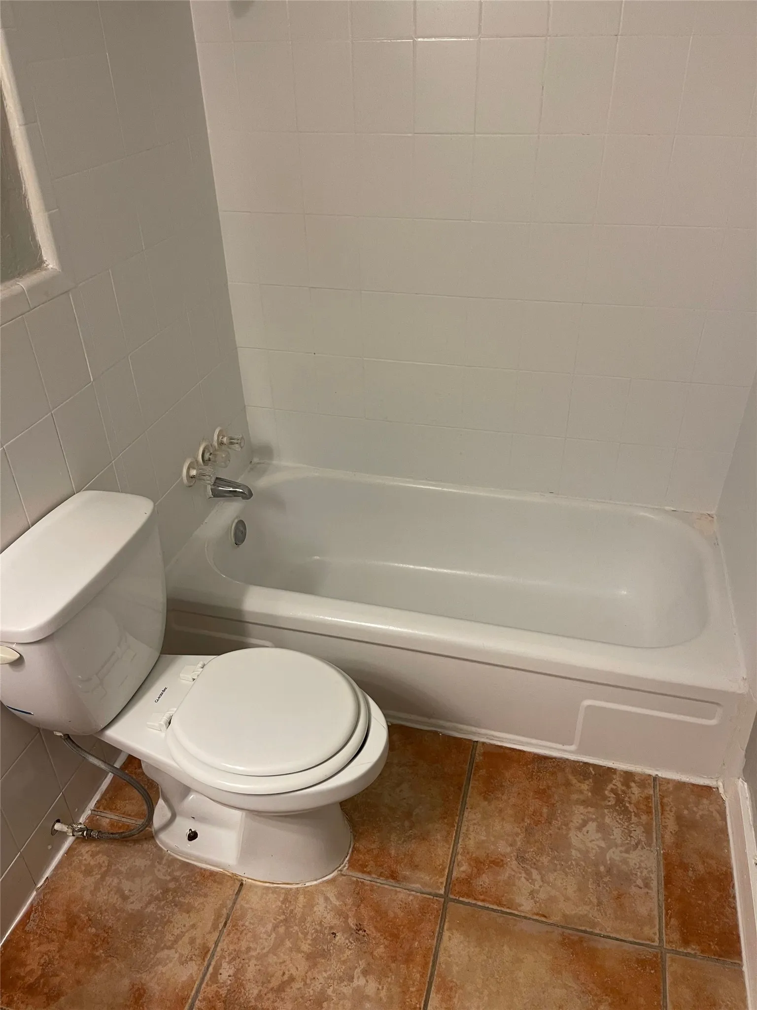 White ceramic wall tiling surrounds a tub with chrome fixtures
