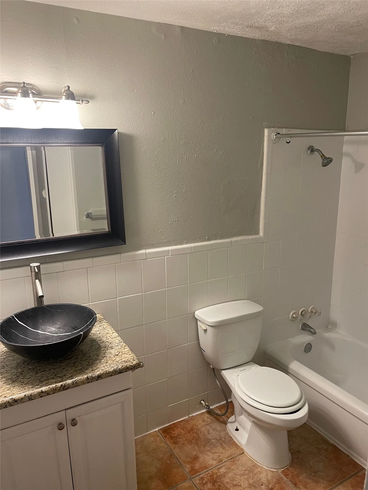 Vanity with a vessel sink, stone-look countertop, and white cabinetry