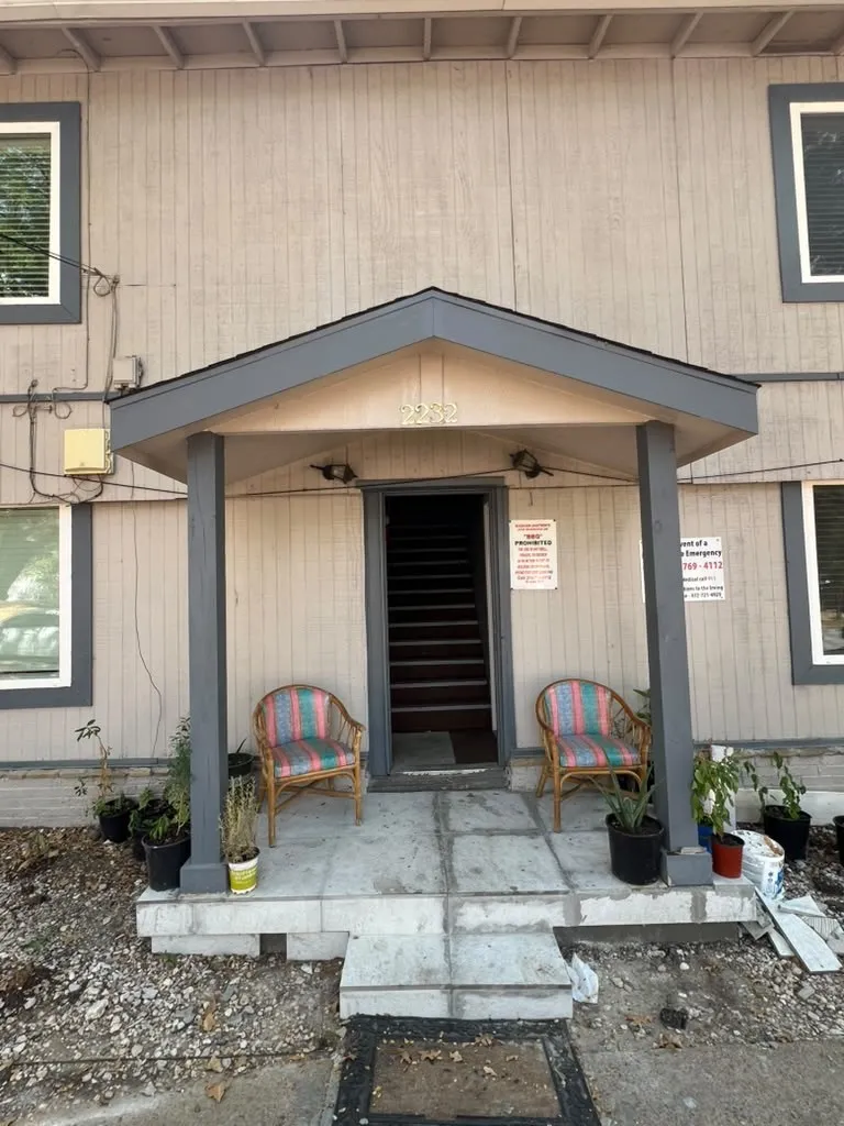 Entryway featuring a covered porch, wood-finish siding, and prominent windows with white framing