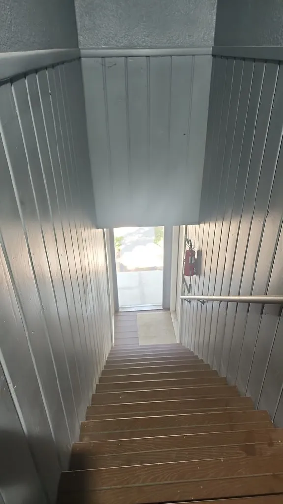 Stairwell with wood-finish stairs, beadboard wall paneling, and a metal handrail