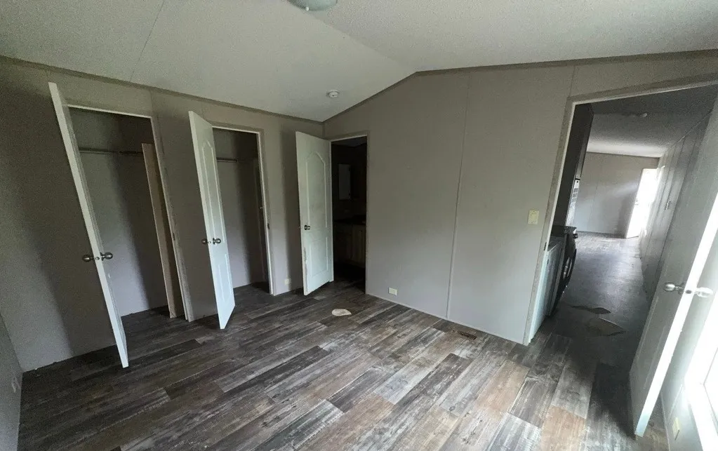 Wood-finish flooring with multiple paneled doors and a semi-flush mount ceiling light