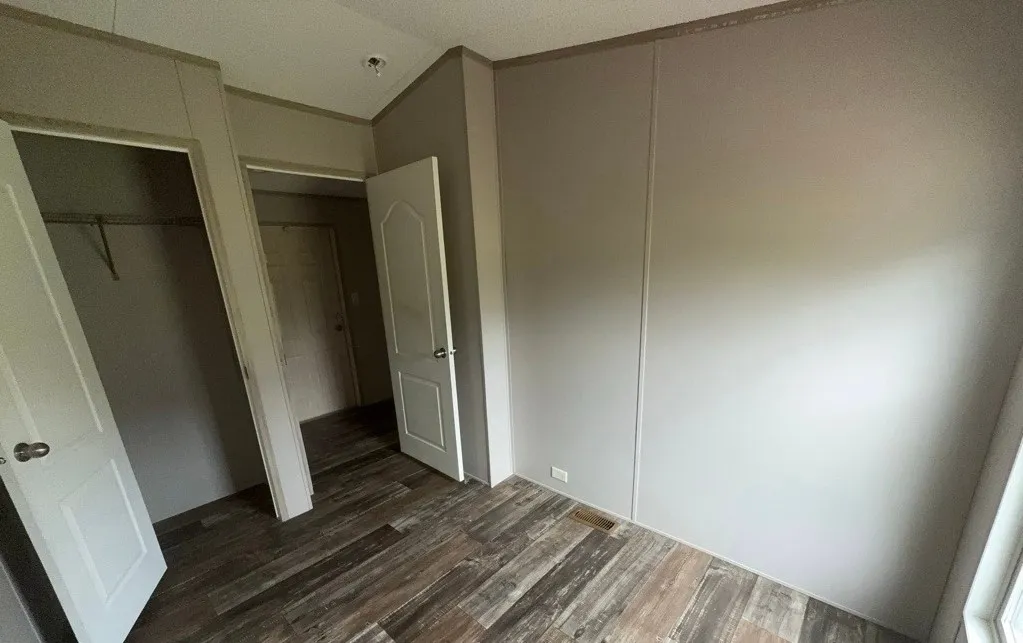 Wood-finish flooring, light-toned wall panels, white interior doors, and a double-door closet