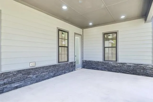 Covered patio featuring plank siding and a stacked stone accent wall