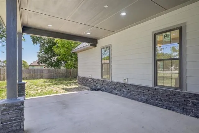 Covered concrete patio with recessed lighting, shiplap siding, and a stone veneer foundation accent