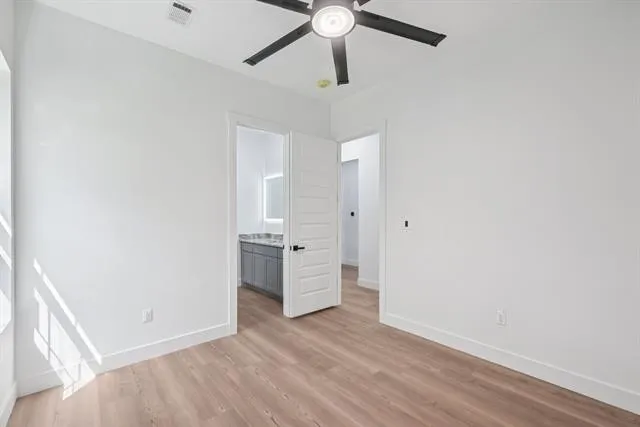 Room with wood-finish flooring, a ceiling fan, and white baseboards
