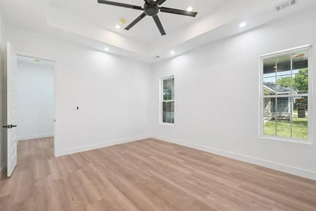 Recessed lighting, ceiling fan, wood-finish flooring, tray ceiling, and white trim