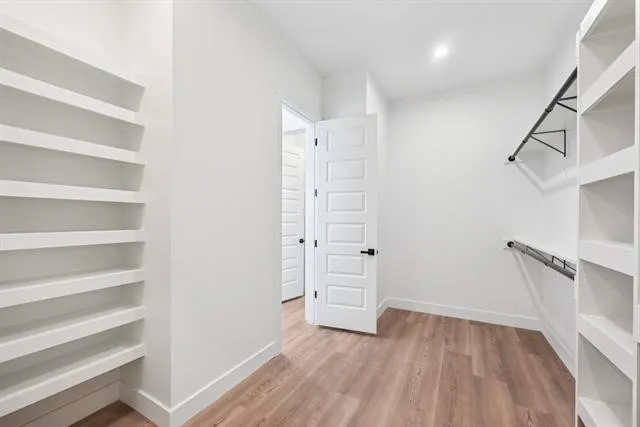 Built-in shelving, wood-finish flooring, recessed lighting, and white paneled doors