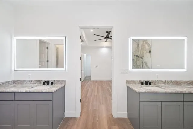 Dual vanities with gray cabinetry and stone countertops