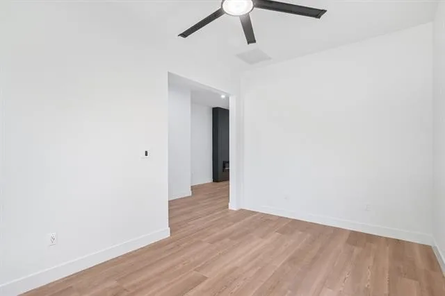 Light wood-finish flooring, white walls, and a contemporary black ceiling fan