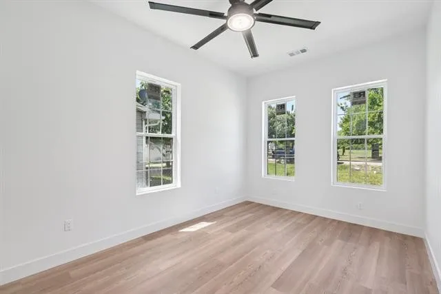 Expansive room featuring multiple windows, wood-finish flooring, a ceiling fan, and recessed lighting