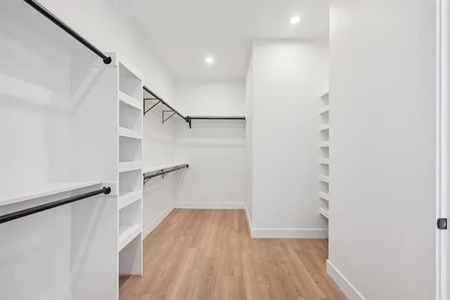 Wood-finish flooring, recessed lighting, built-in shelving, and black rod hanging systems
