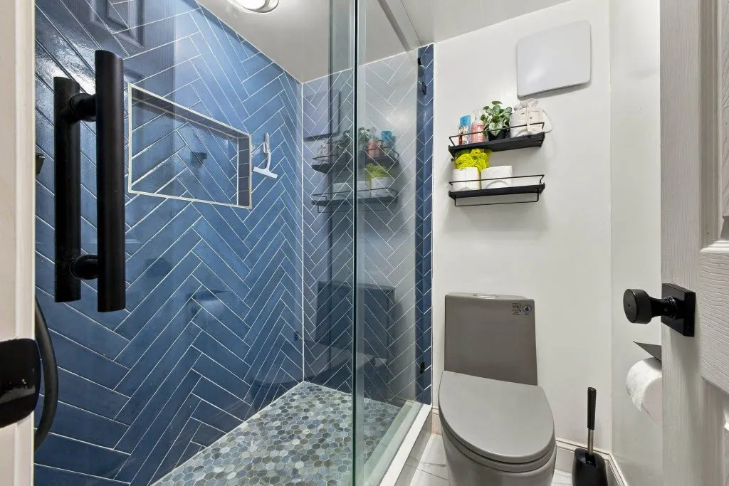 Walk-in shower with blue herringbone tile and a mosaic tile floor
