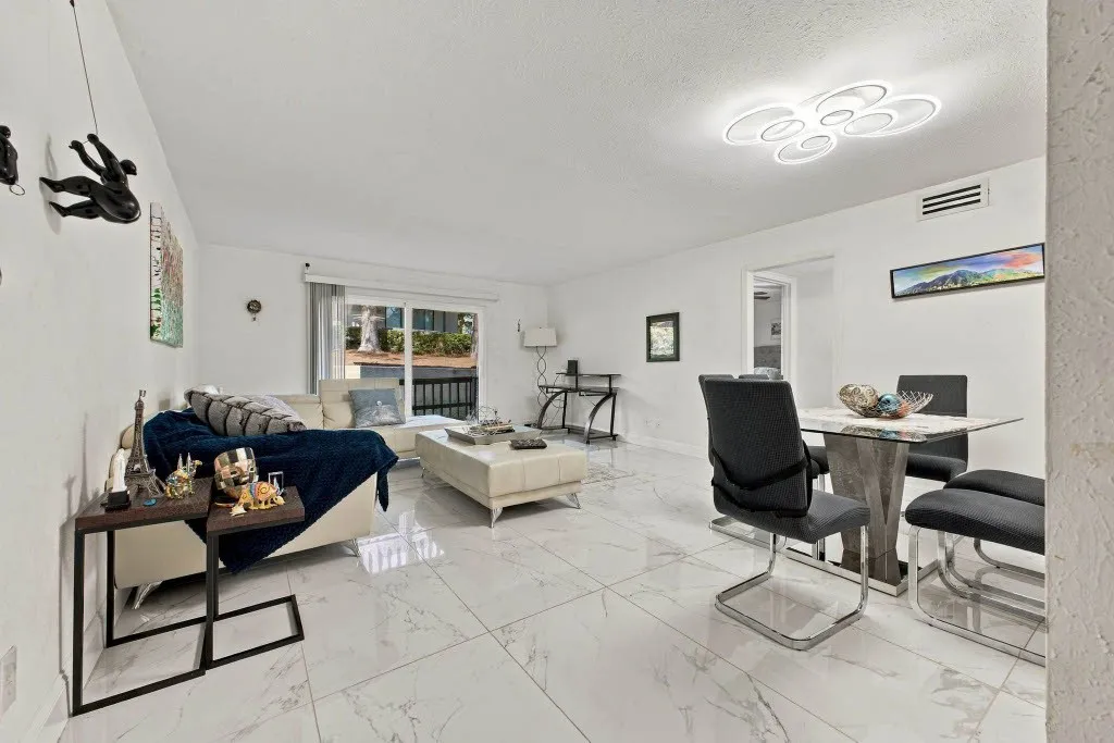 Open concept living area featuring polished tile flooring, a modern flush-mount ceiling light, and a dining area with a glass-top table