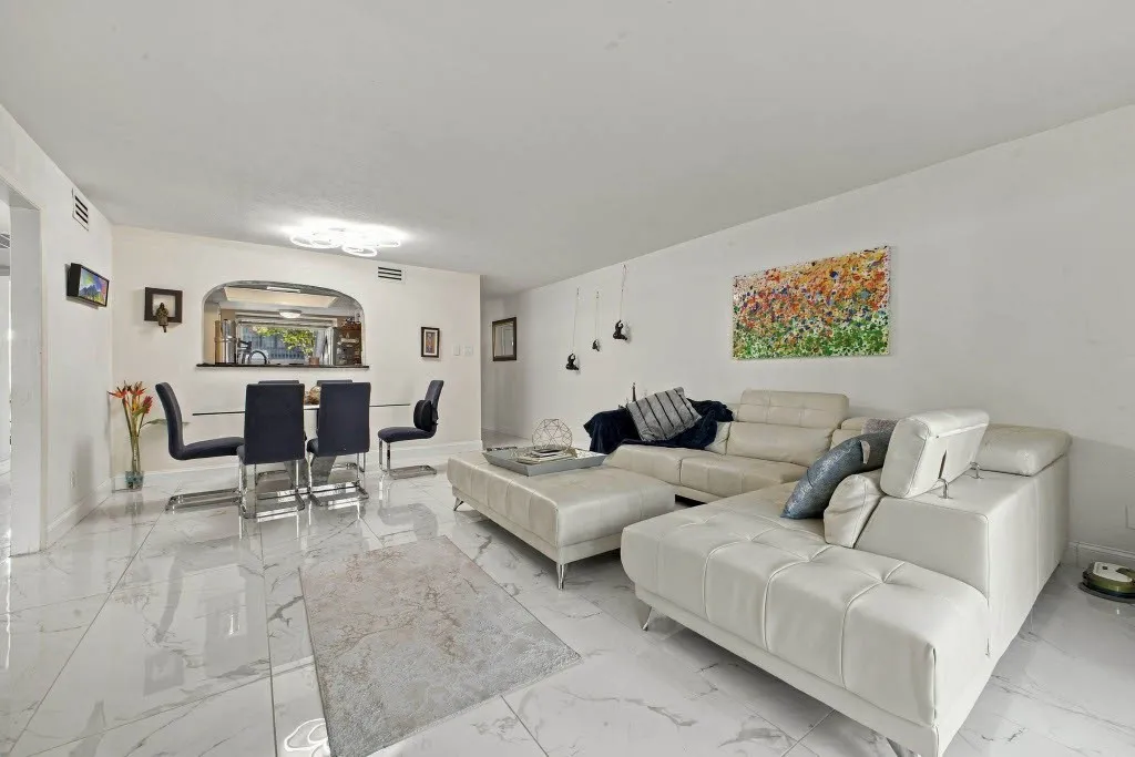Open-concept living space featuring high ceilings, white walls, and large format tile flooring