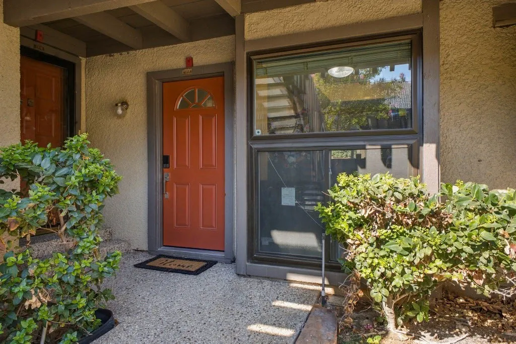 Entryway featuring a panel door with an arched lite, an adjacent fixed window, and a textured stucco exterior