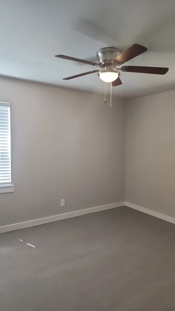 Wood-finish flooring, neutral wall tones, window with blinds, and ceiling fan with integrated lighting