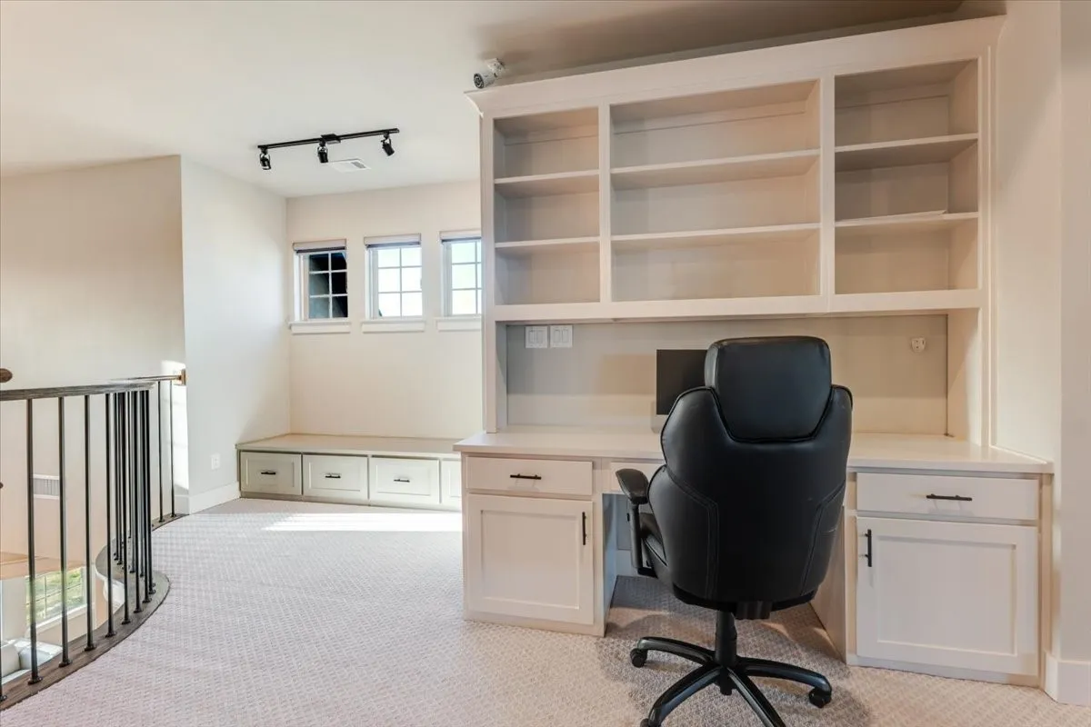 Built-in desk with upper shelving, integrated cabinetry, and track lighting