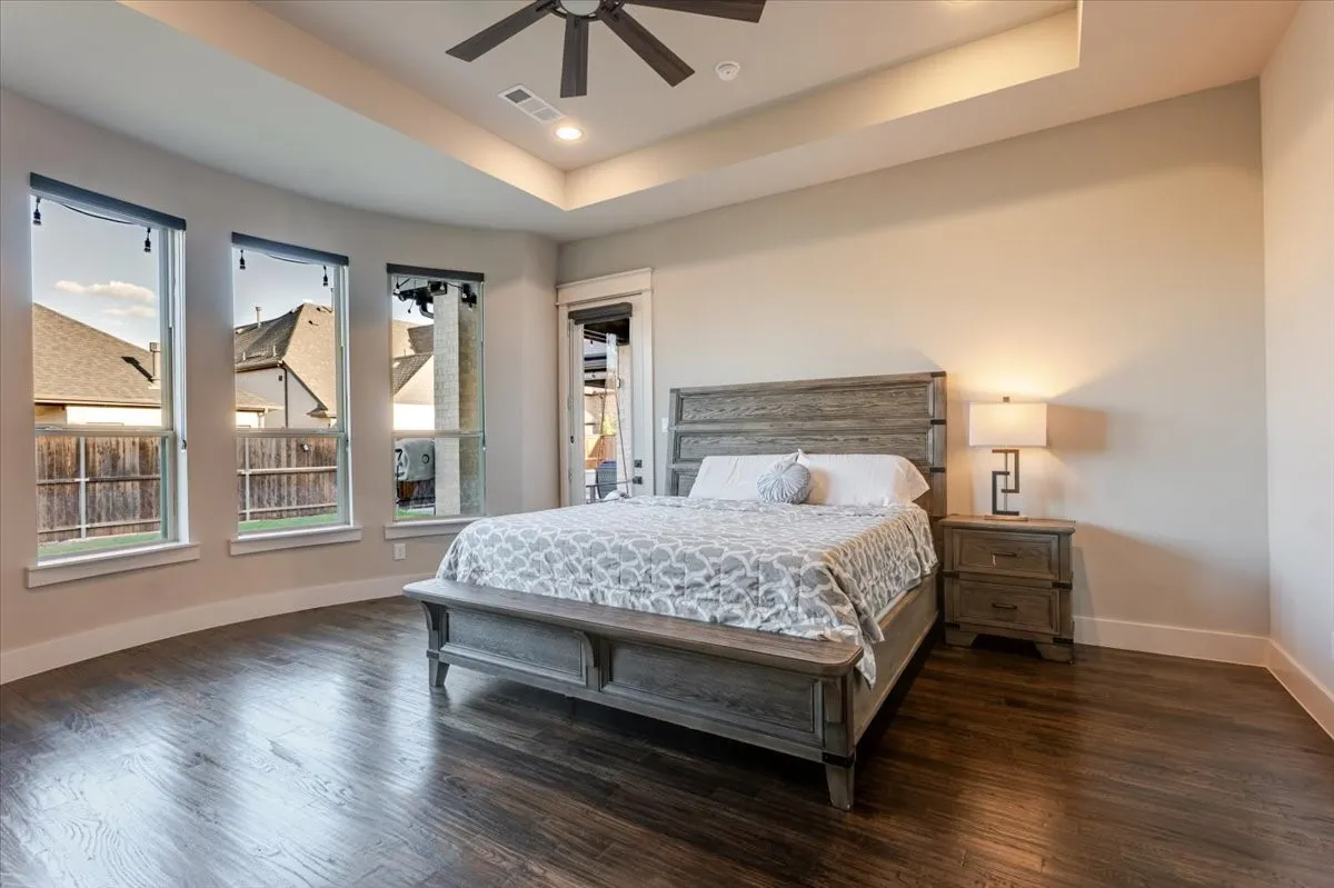 Recessed ceiling with an integrated fan, wood-finish flooring, and multiple tall windows