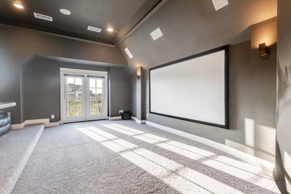 Projector screen, wall sconces, recessed lighting, French doors, and light-toned carpeting