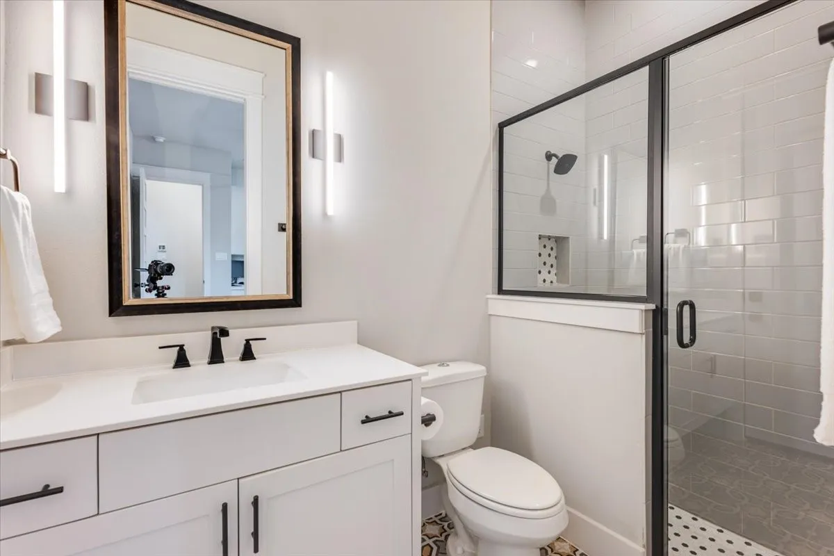 White vanity with integrated sink, black hardware, and wall-mounted lighting