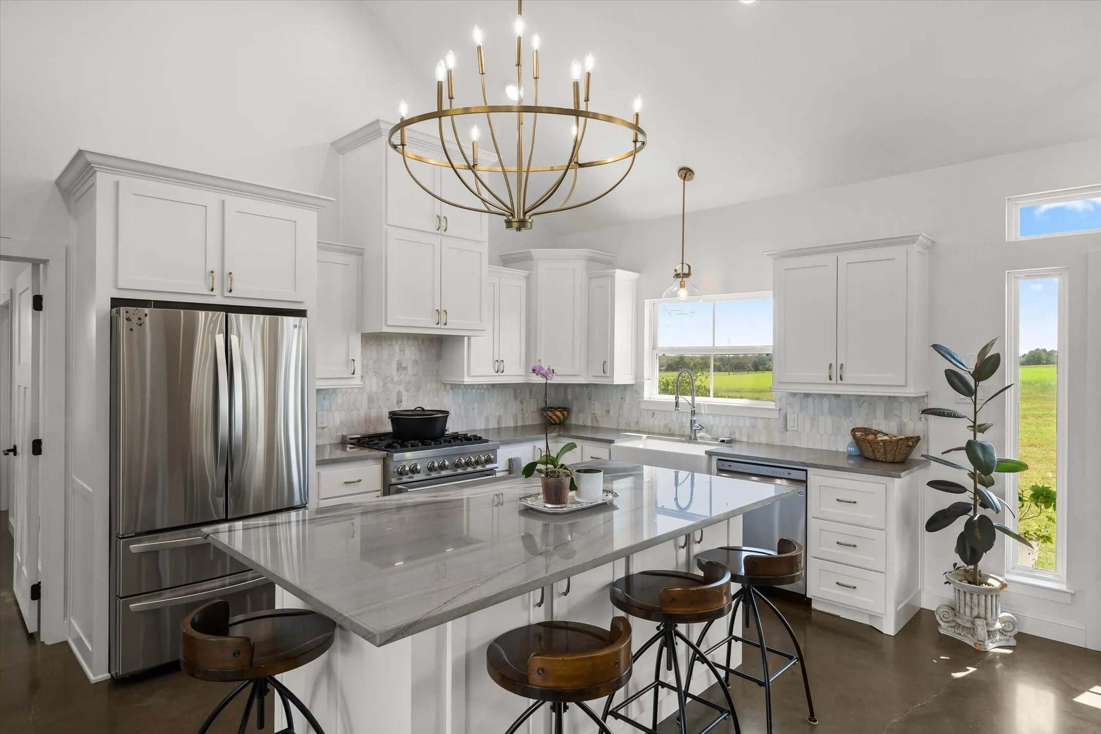 Gourmet kitchen featuring a large central island with seating, stainless steel appliances, white shaker cabinetry, a tile backsplash, and a farmhouse sink