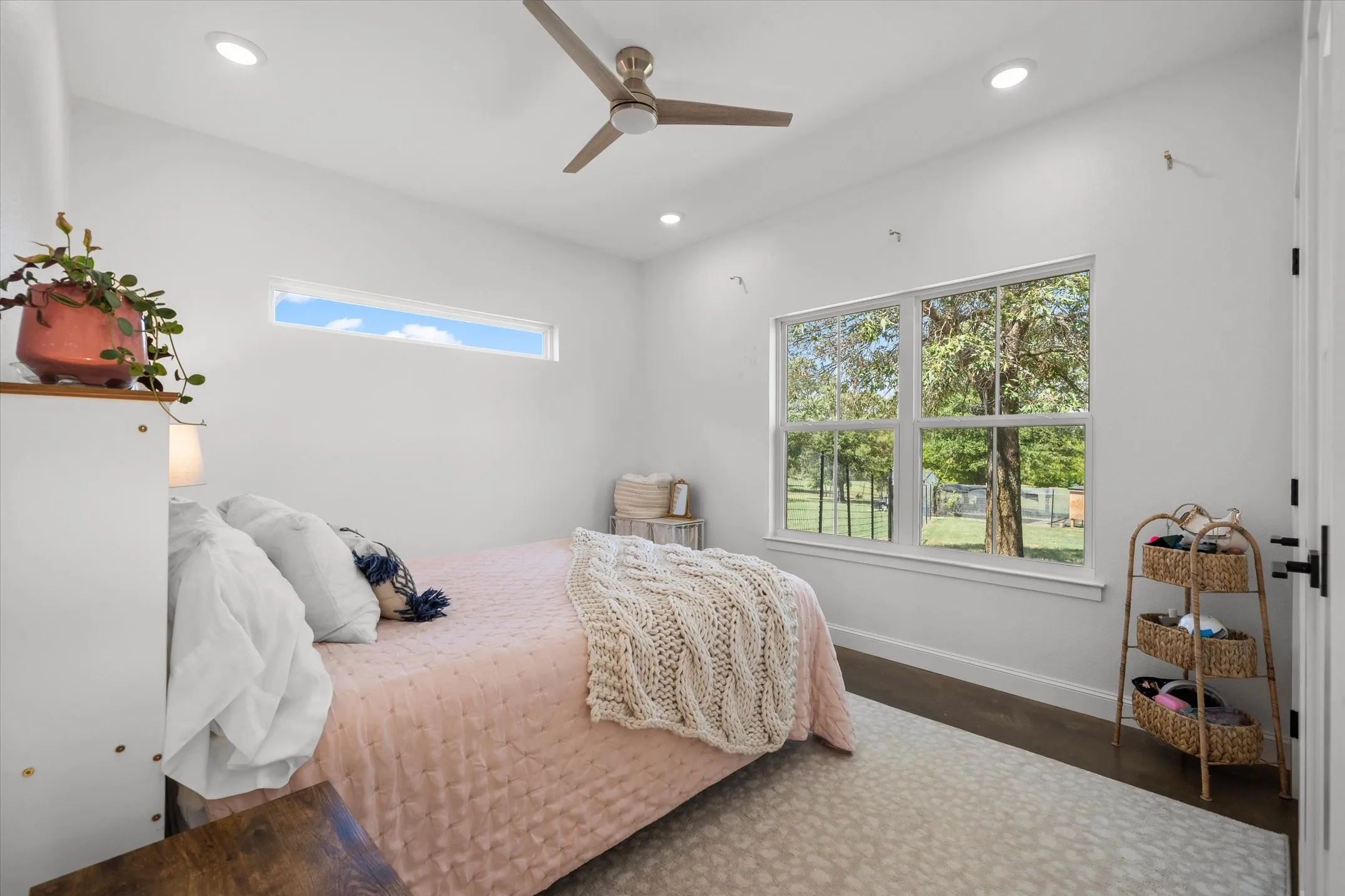 Recessed lighting, a ceiling fan, and dark wood-finish flooring complement the bright white walls