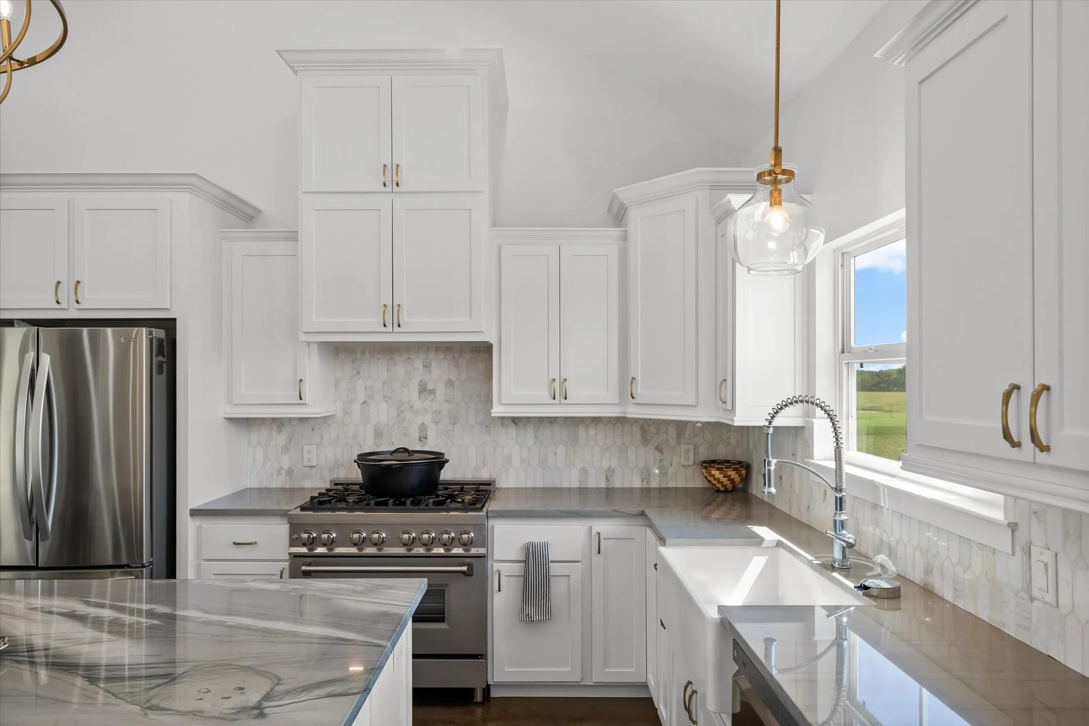 White shaker cabinetry, stainless steel appliances, patterned tile backsplash, deep basin sink, and vaulted ceiling