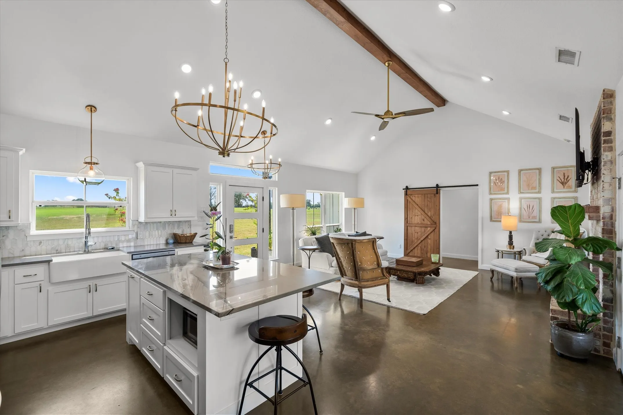 Vaulted ceiling with exposed beam, kitchen island with built-in microwave, farmhouse sink, white shaker-style cabinetry, and wood-finish flooring