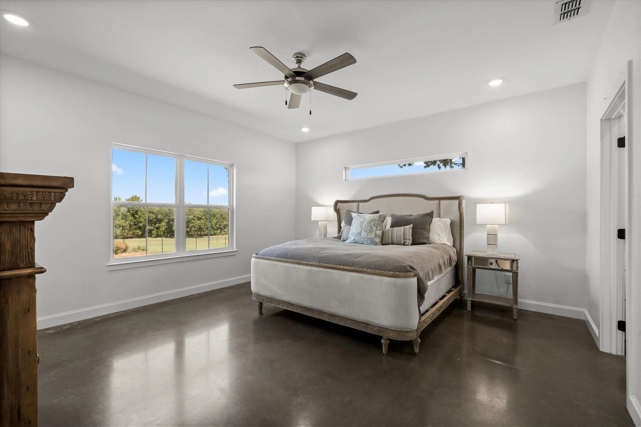 Polished concrete flooring, recessed lighting, ceiling fan, transom window, and white trim