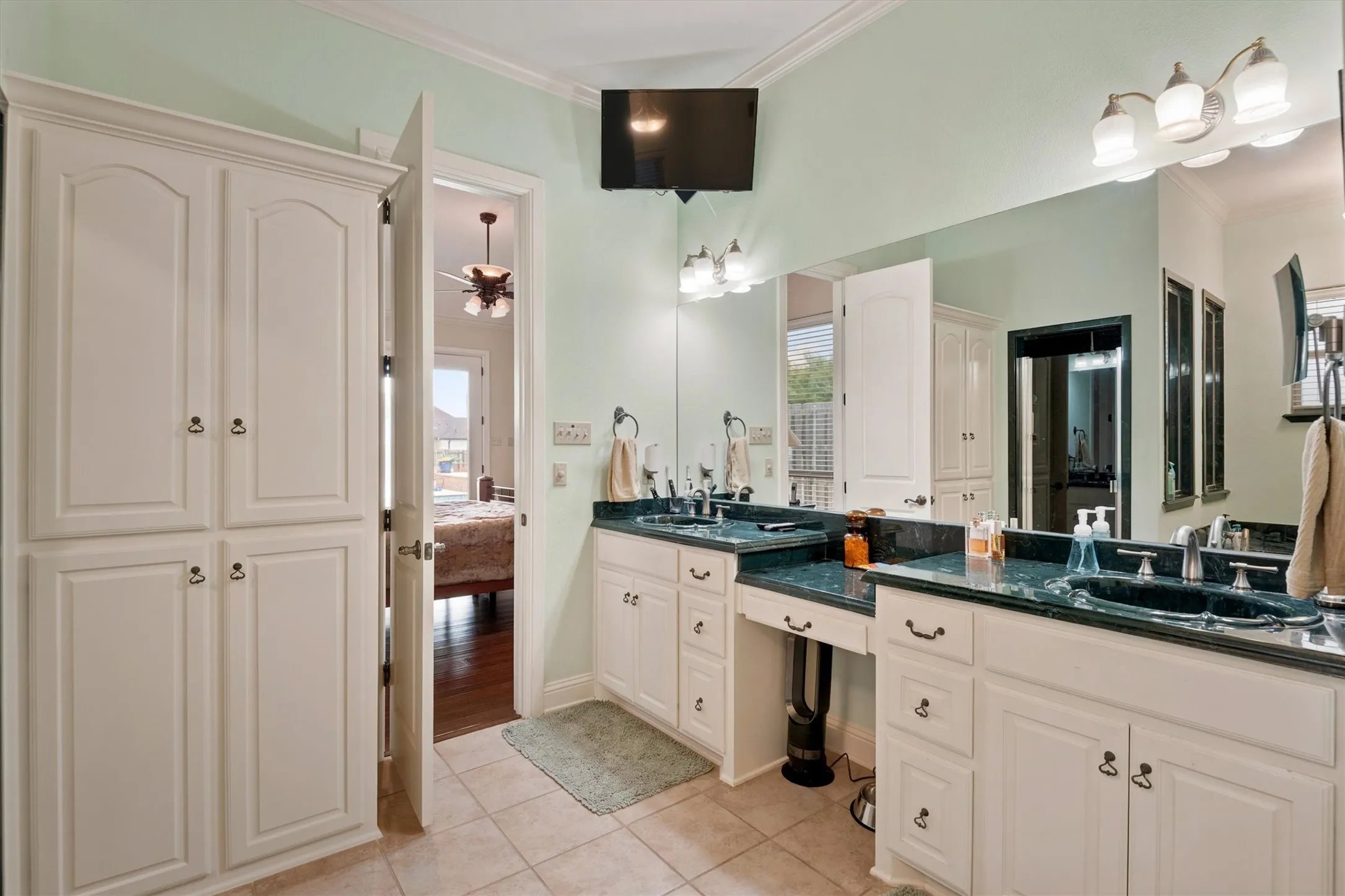 Dual vanity with integrated sinks, ample storage cabinetry, and a dedicated makeup counter