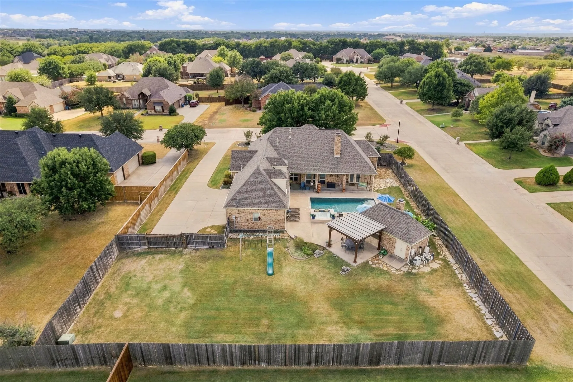 Rear yard featuring a fenced perimeter, a swimming pool, covered patio, and an accessory building