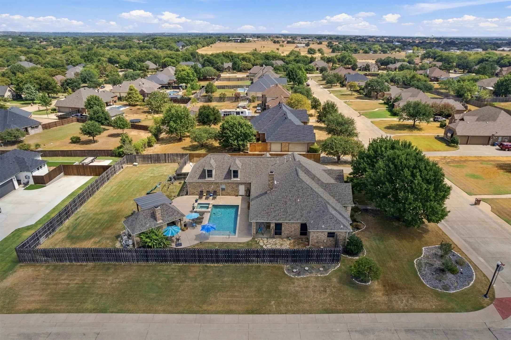 Brick exterior residence featuring an outdoor pool, covered patio, and a fenced yard