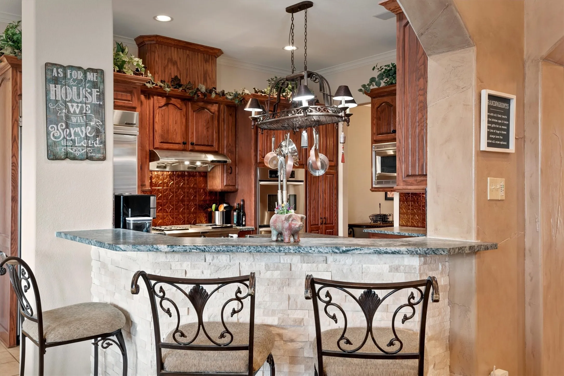 Kitchen pass-through with stone veneer bar base, granite countertop, and custom wood cabinetry