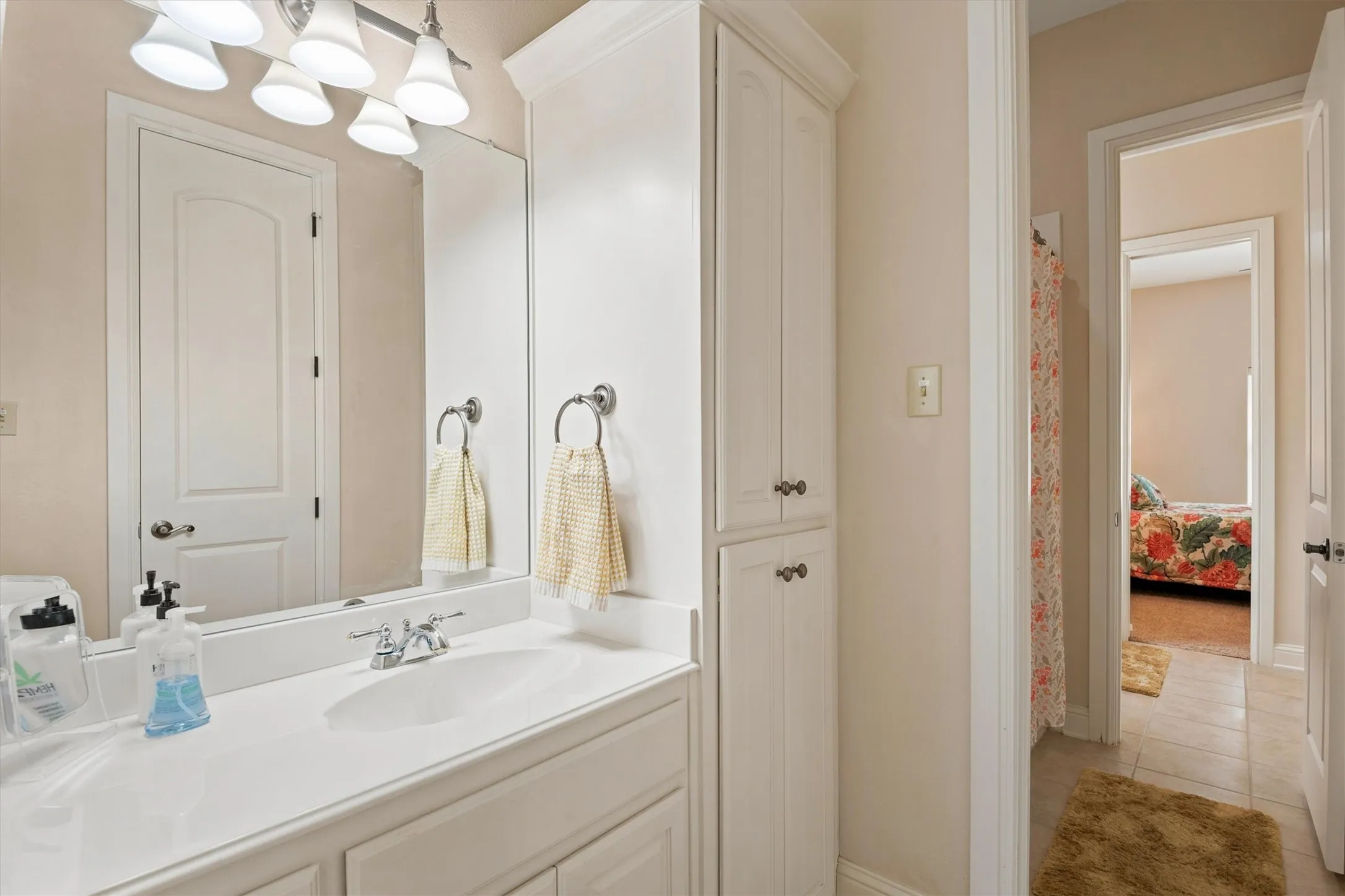 White vanity with an integrated sink and chrome faucet, large frameless mirror, and integrated lighting