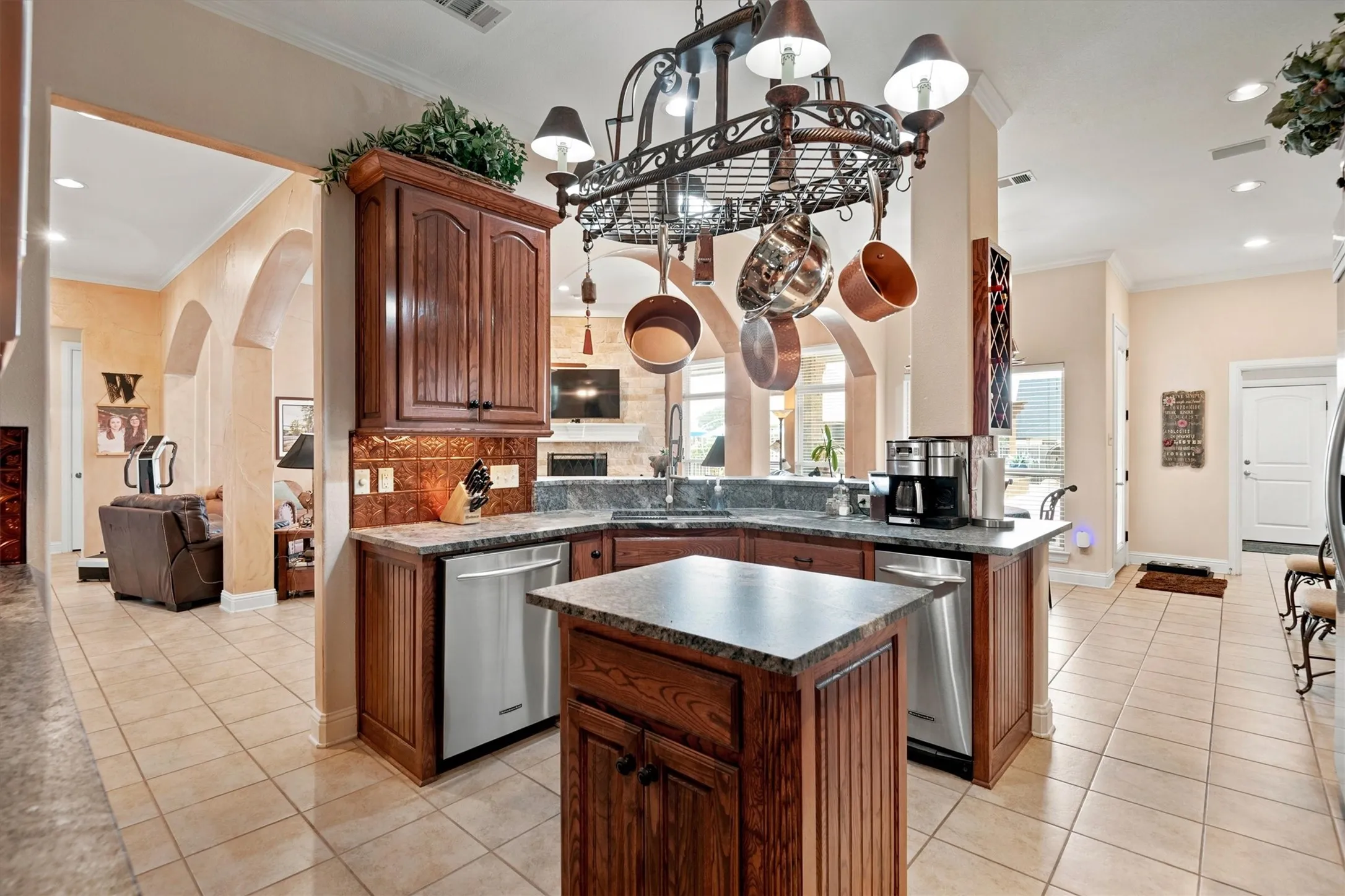 Kitchen featuring wood cabinetry, stainless steel appliances, a central island, tile flooring, and a pot rack light fixture
