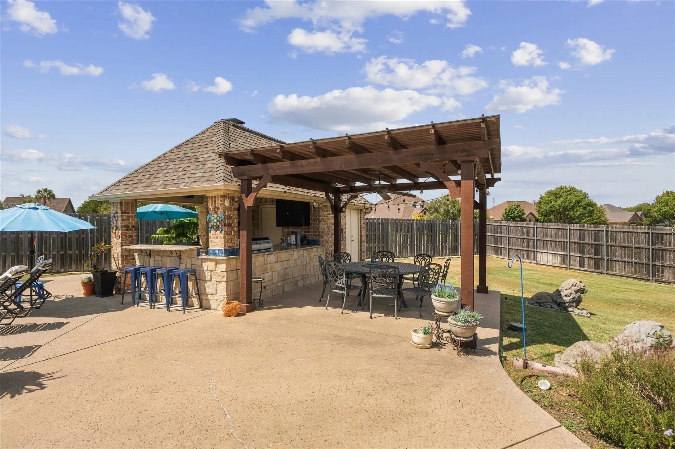 Outdoor kitchen featuring stone construction, a built-in bar, and a television