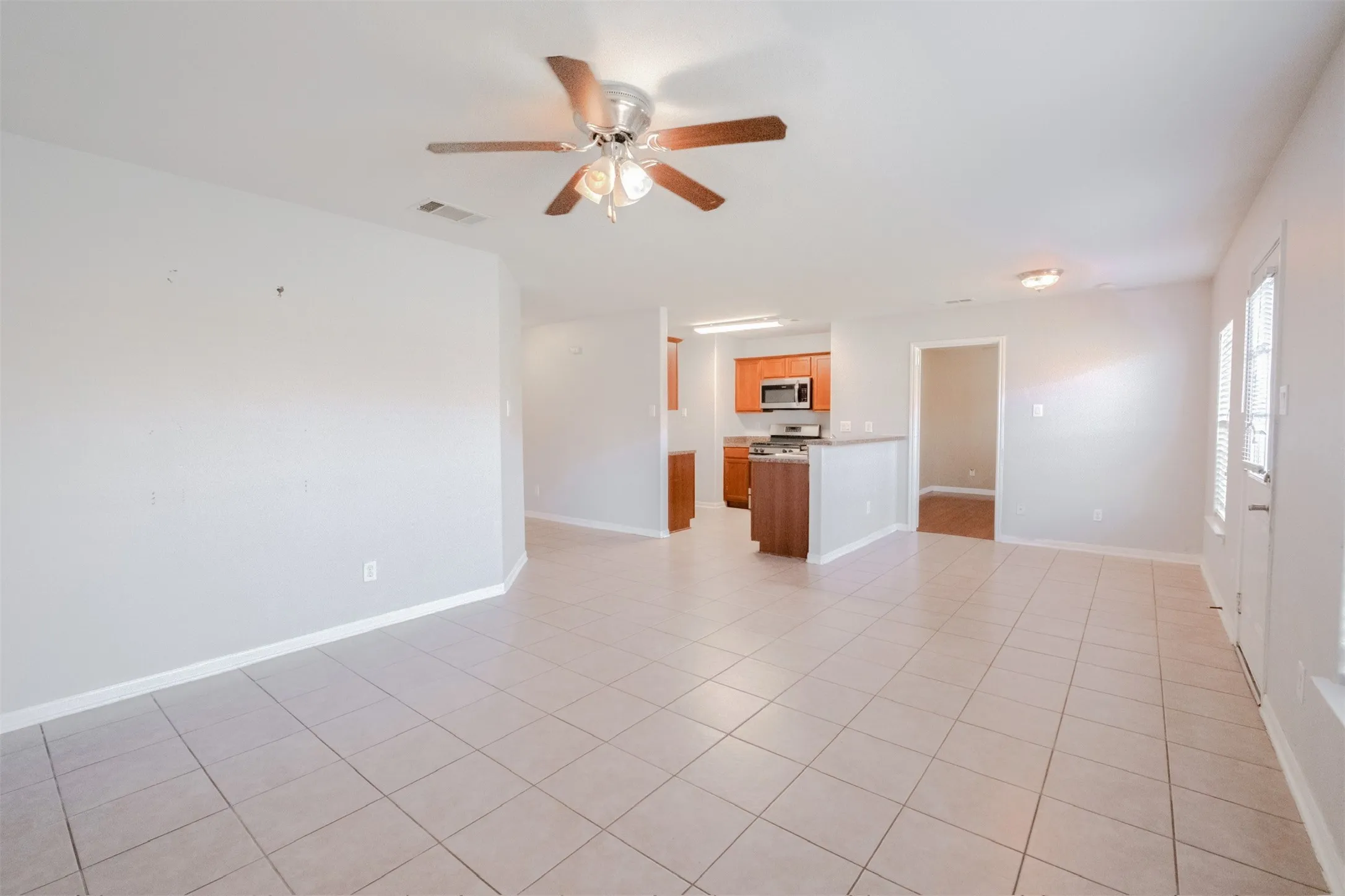 Unfurnished living room with ceiling fan and light tile patterned floors