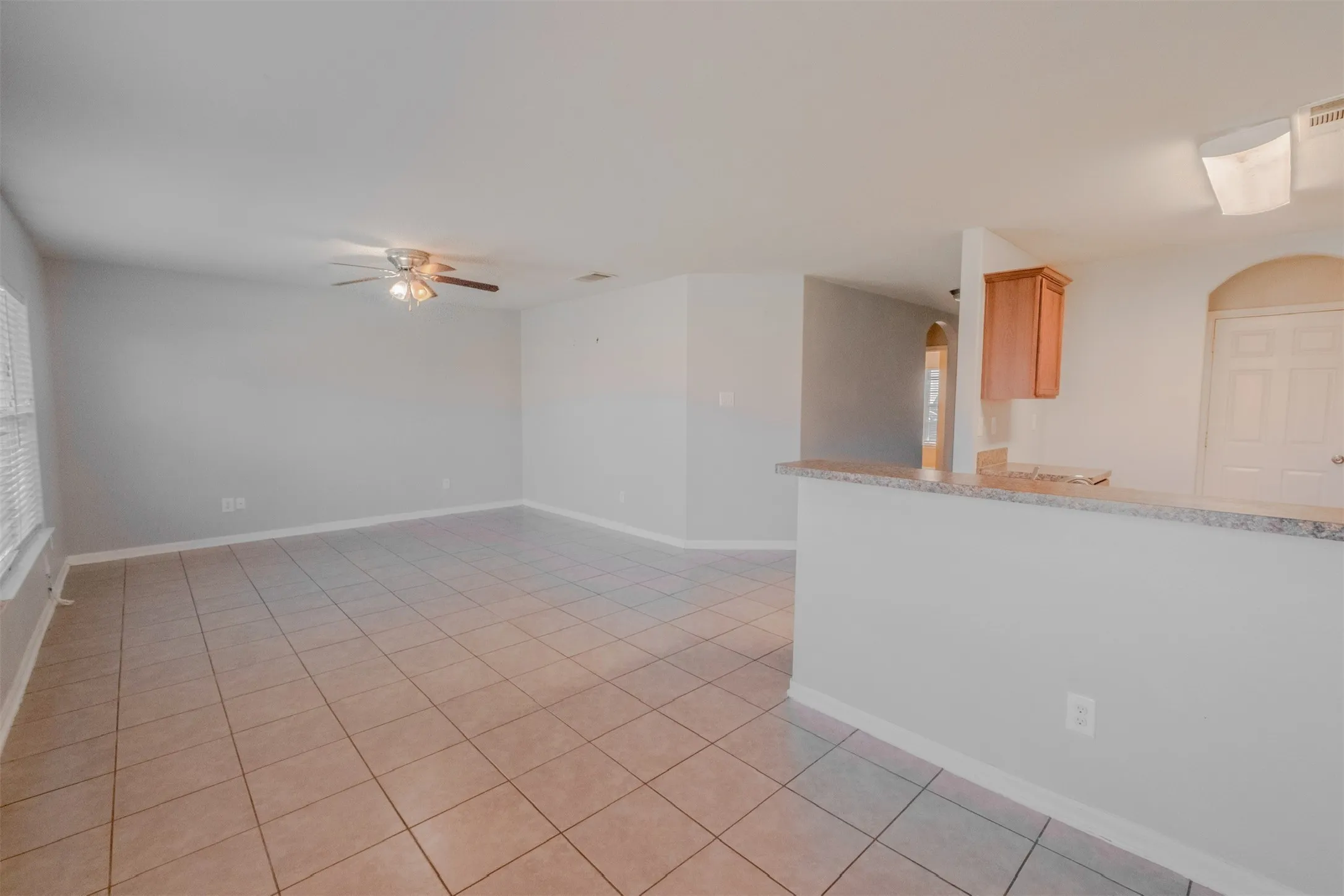 Spare room featuring arched walkways, light tile patterned floors, and ceiling fan