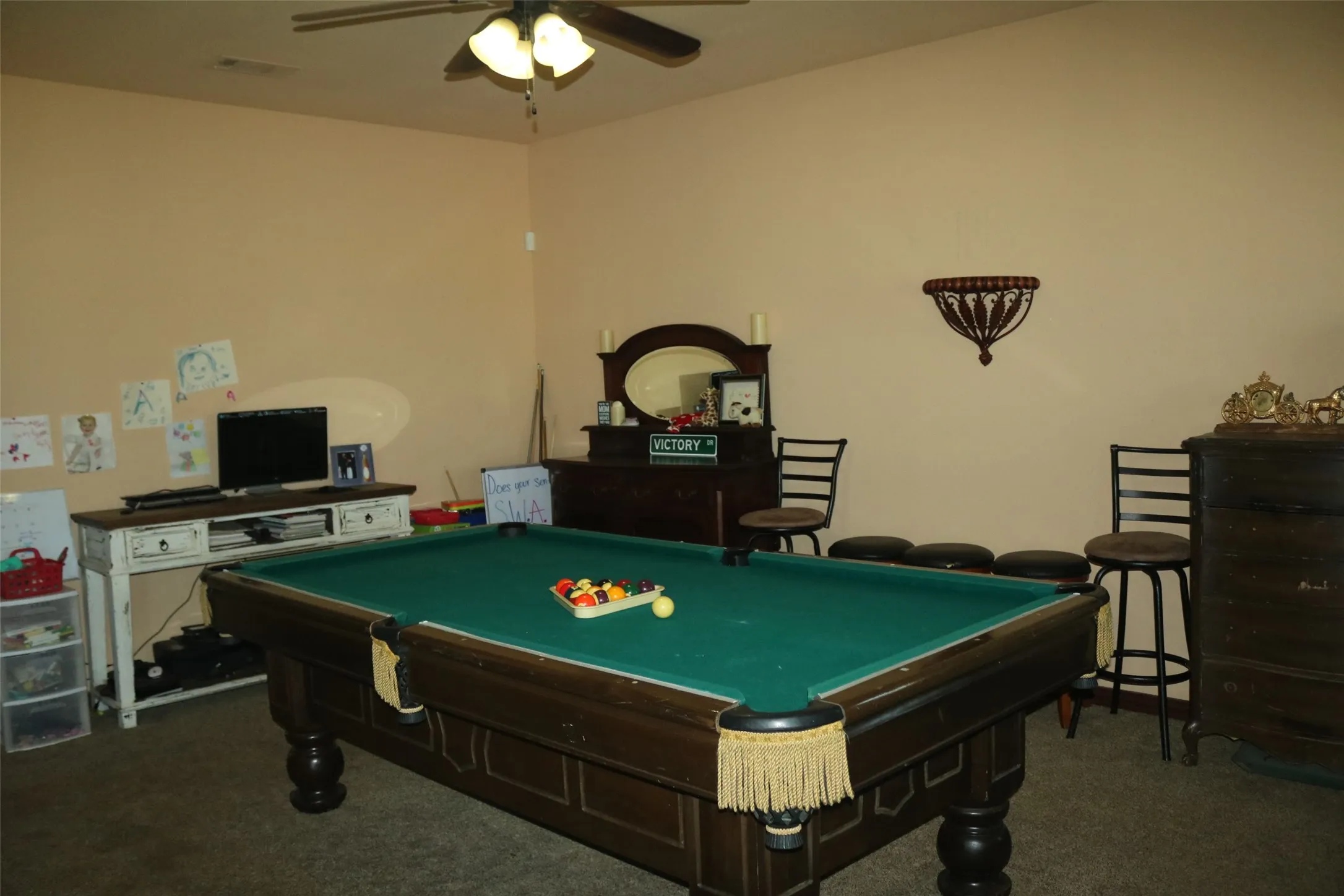 Carpeted room with a ceiling fan light fixture and neutral wall paint